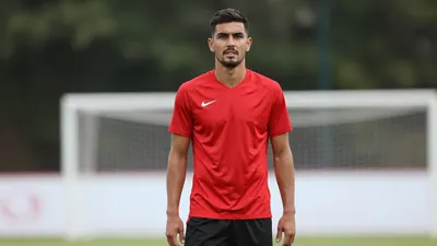 A 24-year-old male soccer defender in a clean solid red jersey and black shorts, standing confidently in a training session