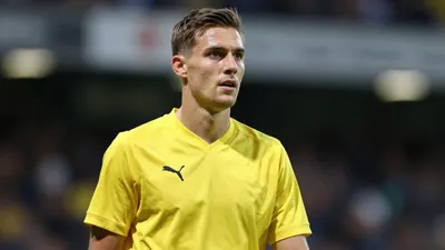 A mid-30s anonymous KV Mechelen midfielder, wearing a solid yellow jersey, captured waist-up with a focused expression...