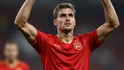 Photorealistic portrait of a KV Mechelen player in the new 1946-inspired home shirt, mid-celebration with arms raised...